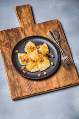 Dumplings with meat, onions and bacon on black plate. Traditional Polish dumplings