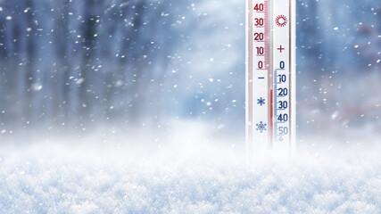 Thermometer in the snow on a background of trees during a snowfall shows 15 degrees below zero
