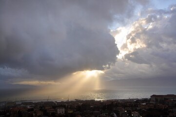Fototapeta na wymiar Dramatic blue sky with sun whose rays pierce the cloud and reflect to the sea