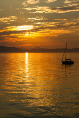 Fototapeta na wymiar Vertical view of a sailboat on Lake Champlain at sunset
