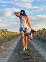 Young girl in shorts and white T-shirt is walking along country road