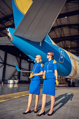 Elegant stylish women air hostesses posing at the photo camera in the outdoors at the airport