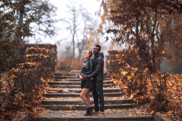 Interracial couple posing on stairs in blurry autumn park background