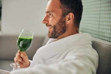 Good-looking young man drinking fresh green smoothie
