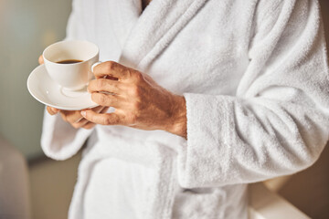 Male hands holding cup of coffee and saucer