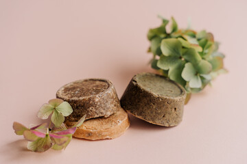 hand-made solid dry shampoos of a round shape on a plain beige background. natural hair cosmetics. soap for handicraft from chamomile and eucalyptus. environmentally friendly products, no waste