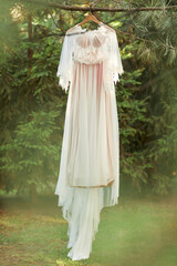 wedding dress hanging on tree in the forest. vintage or rustic