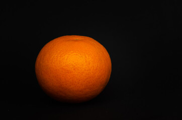 A tangerine on black background, a simple image of a mandarin.

