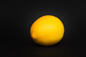 A yellow lemon on black background.