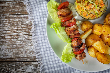 Shish kebab served with roasted potatoes and salad.