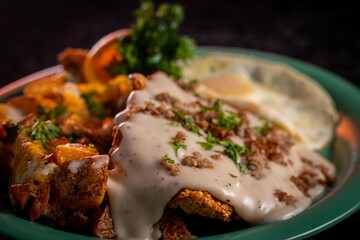 A mouth watering image of a chicken fried steak with gravy and eggs.