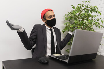 Young office worker wearing red cap and face shield pretends to be confused