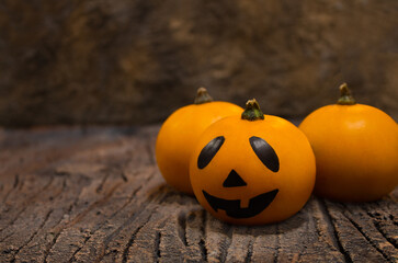 Halloween dark card. Three orange pumpkins. One of them is Jack. They lie in a basket on the bark of a tree. Copy space