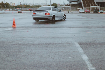 Cars are drifting in the old parking lot. Rain drift. Gray photo processing, atmosphere. Racing in...