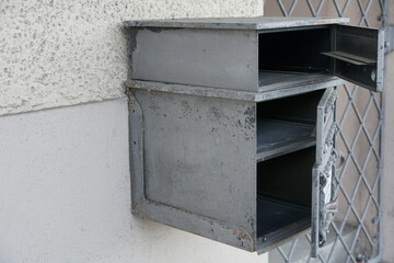 A home letterbox, mailbox or post-box with three compartments made of grey metal attached on the wall of a family house in a Swiss village in canton Zurich. 