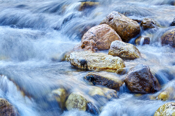 cascade of waterfalls of a mountain river among the boulders, the water is blurred in motion
