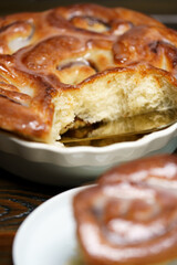 Date cinnamon buns in light blue ceramic dish. Dark wooden table, high resolution