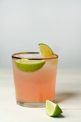 Paloma cocktail served with grapefruit and lime slices. White wooden background, high resolution