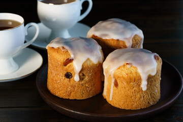 Traditional Easter kulich pastry served with white porcelain cups of tea. Wooden table, high resolution