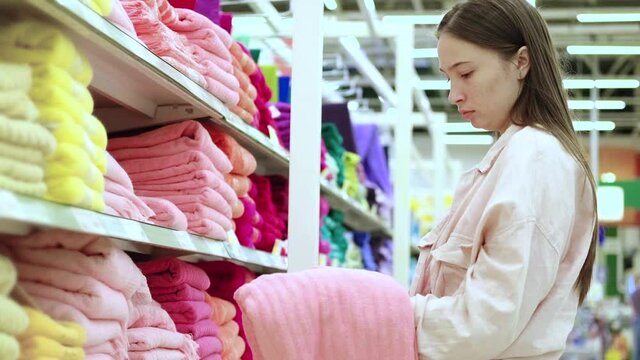 young housewife is buying towel in hypermarket