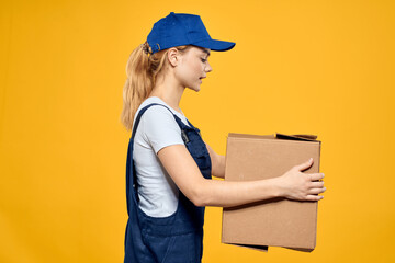 Woman with a box of construction tools and in a cap on a yellow background repair construction industry