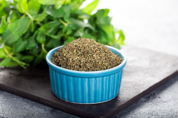 Dried peppermint in a white bowl and a bunch of fresh mint, on wooden background. Food background.