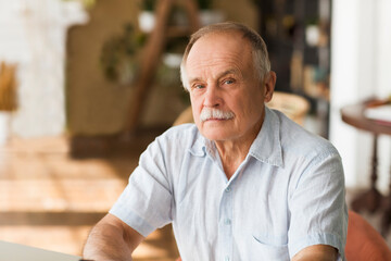 portrait senior man thinking and looking at camera at home