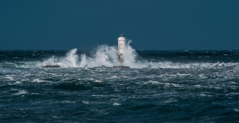 The lighthouse of the Mangiabarche shrouded by the waves of a mistral wind storm
