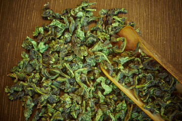 chinese oolong  tea te guan yin with wooden spoon on dark brown close up