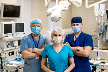 Fototapeta na wymiar Team of surgeons posing in bright modern surgery room. Operating theatre. Modern equipment in clinic. Emergency room.