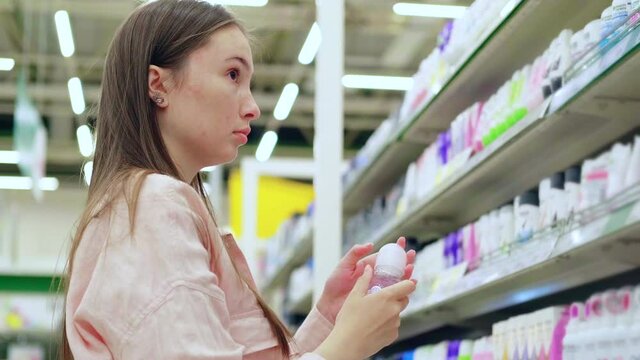 female buyer is choosing roll-on deodorant in cosmetic shop