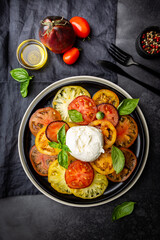 Fototapeta na wymiar Delicious caprese salad with ripe colorful tomatoes and mozzarella cheese with fresh basil leaves. Italian food, top view