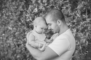 father and daughter leaned their heads to each other on the background of a hedge
