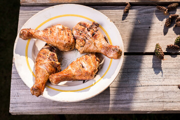 Fried chicken legs in a plate on a wooden table/Fried chicken legs in a plate on a wooden table. Top view. Sanny day.