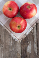 Three red apples on the wooden background. Autumn mood. Organic and healthy food. Rustic style. Mouth-watering apples. Copy space. Close up. Apples in my garden.
