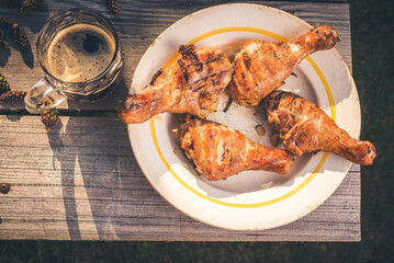 Fried chicken legs in a plate and a glass of beer on a wooden table/Fried chicken legs in a plate and a glass of beer. Top view.