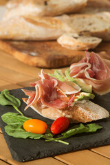 bruschetta with ham (bacon) and avocado on a black plate. The option of a beautiful and healthy Breakfast or snack