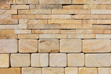 The wall is composed of hewn round stones of yellow sandstone in the lower half and rough rectangular tiles at the top.