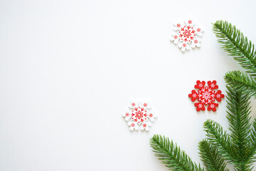 Christmas white background with fir branches and white and red snowflakes. Xmas, New Year's wallpaper. Winter holiday decorations isolated on white background with copy space. Flat lay, top view.