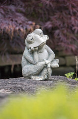 Fototapeta na wymiar Thinking frog sculpture sitting by a pond