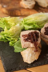 bruschetta with liver pate and onion jam on a black plate and wooden table