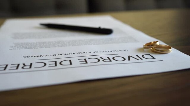 Divorce decree agreement with wedding rings on the table.