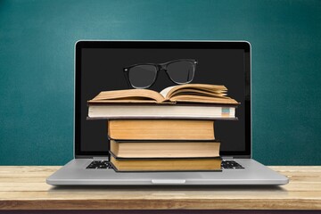 Stack of books with a modern laptop on the table