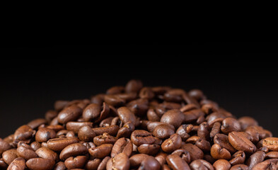 Coffee beans on a black background. Heap of coffee beans. Poured coffee close-up