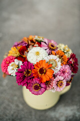 Bouquet of colorful zinnia flowers in a yellow vase