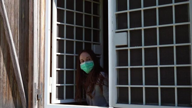 Happy woman in quarantine looking out the window and clapping hands for medical staff, grateful applause for doctors and nurses who saving human lives during coronavirus infection in Europe