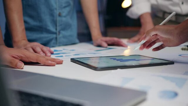 Millennial Asia businessmen and businesswomen meeting brainstorming ideas about new paperwork project colleagues working together planning success strategy enjoy teamwork in small modern night office.