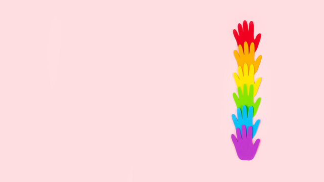 Tolerance, kindness, cooperative, friendship, charity humanitarian aid day concept. Many rainbow color palm hands on pink background with copy space