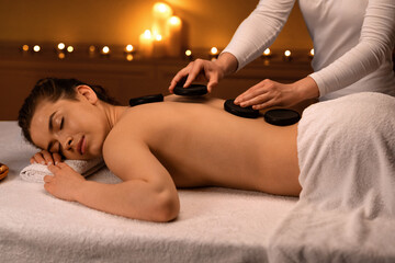 Relaxed lady receiving hot stone massage at modern spa