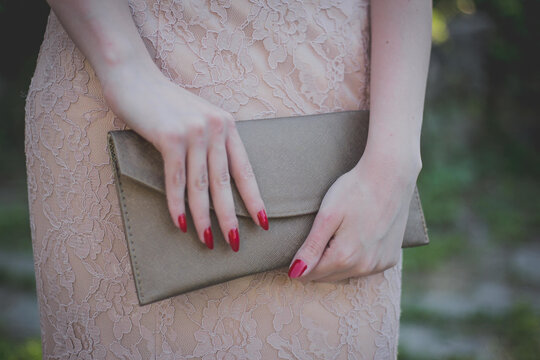 Closeup shot of a fashionable female in a fancy evening dress holding a clatch bag